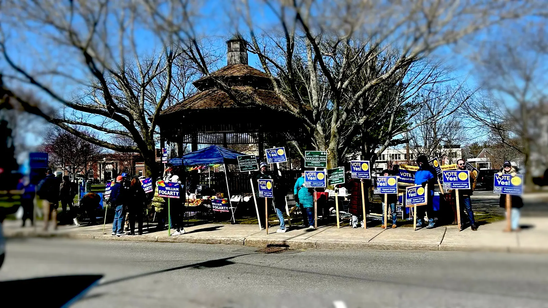 Photo of a group of sign holders at Stoneham town common on election day holding "Vote Yes" signs.
