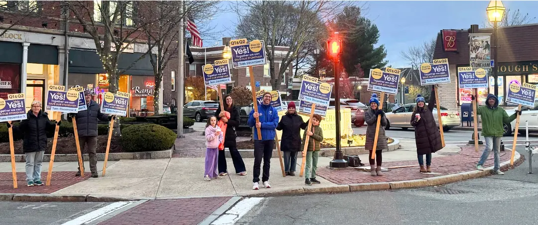 Photo of Stoneham residents holding 'Vote Yes!' signs